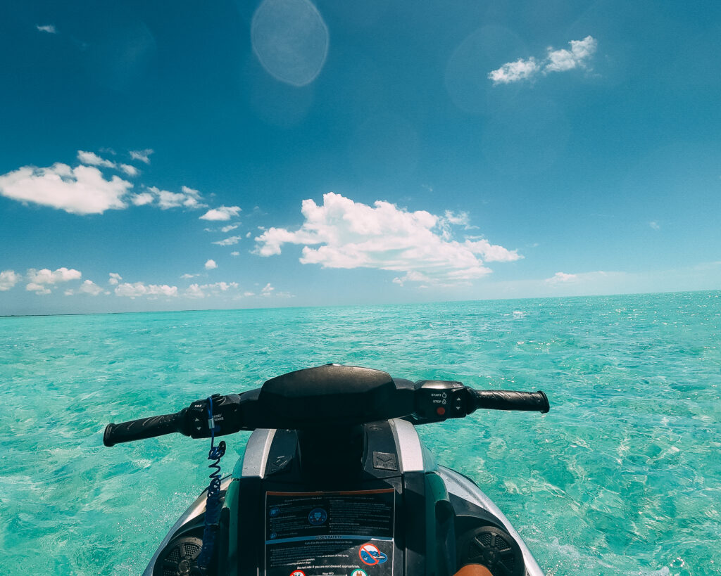 Rider point of view from jet ski handlebars over shallow turquoise water