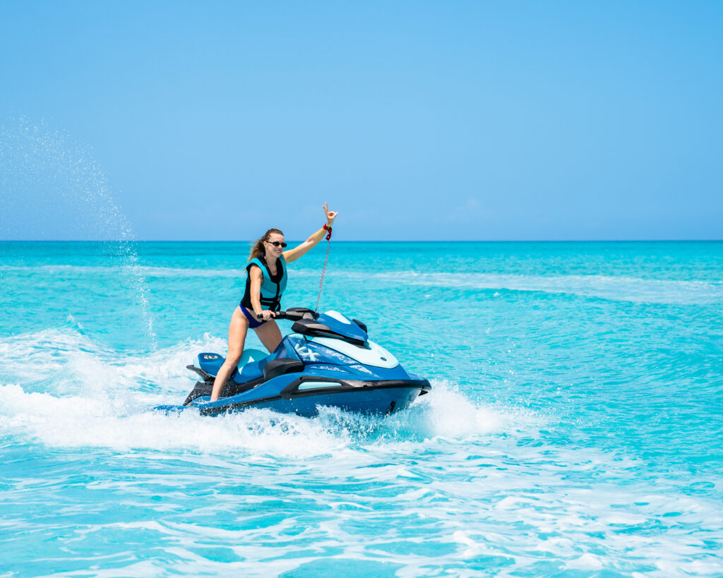 Smiling rider waving from a jet ski on bright turquoise water