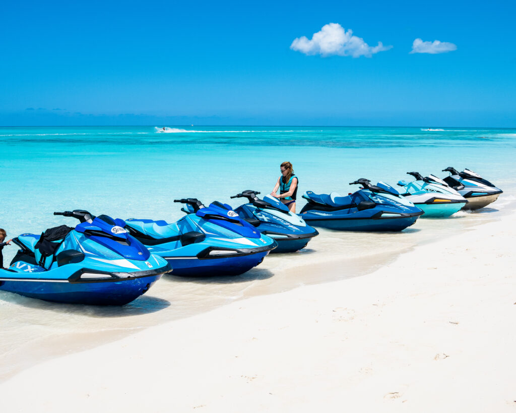 Fleet of blue jet skis lined up on a white sand beach in Turks and Caicos