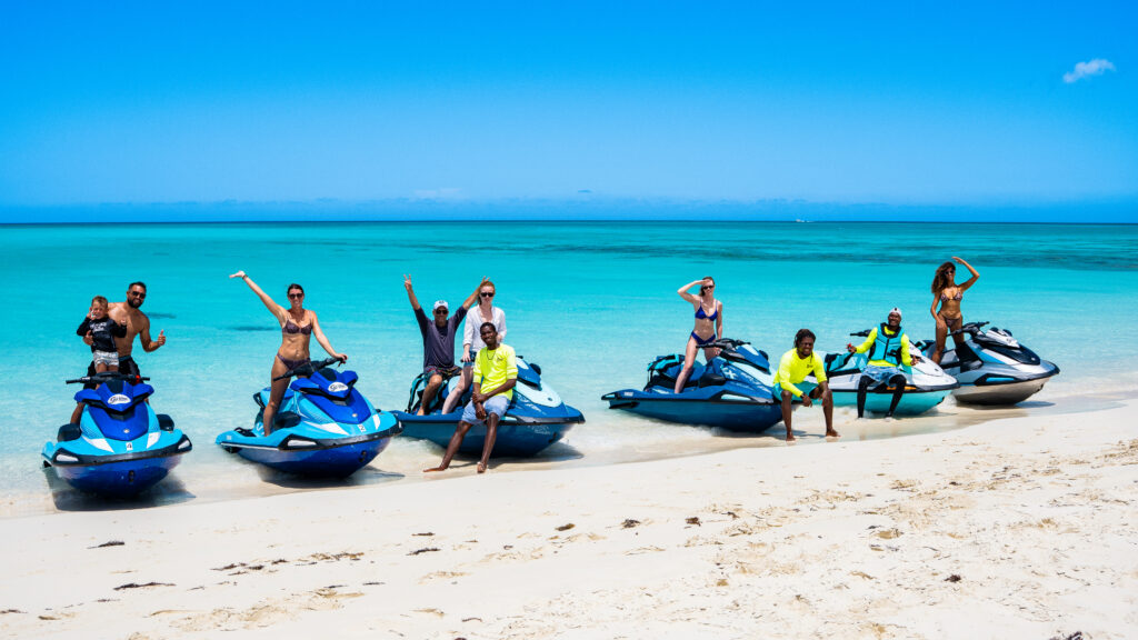 Happy group celebrating next to their jet skis on the beach