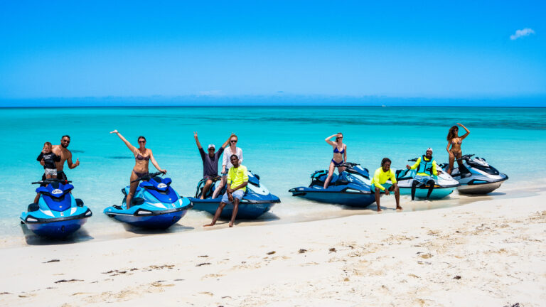 Happy group celebrating next to their jet skis on the beach