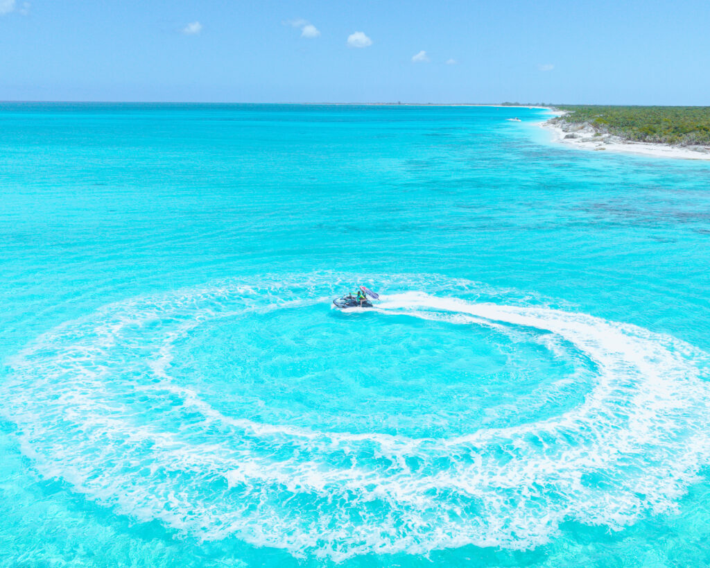 Aerial view of a jet ski carving a circle in turquoise water off Providenciales