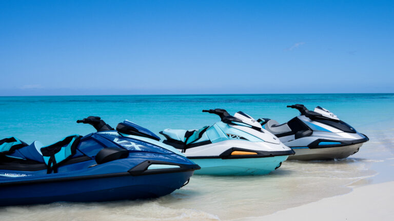 Row of jet skis parked at the water’s edge on a sunny day